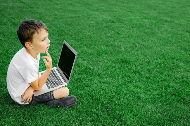 un enfant pensif est assis dans l'herbe qui symbolise l'écoconception web