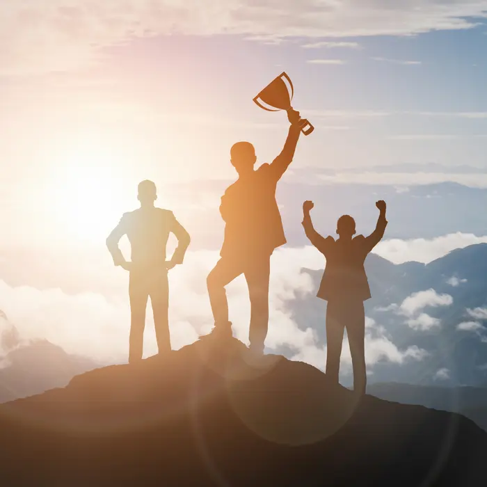 photo d'une équipe triomphante en haut de la montagne couronnée et qui brandit une coupe en vainqueur pour symboliser les performances de l'agence web Laon