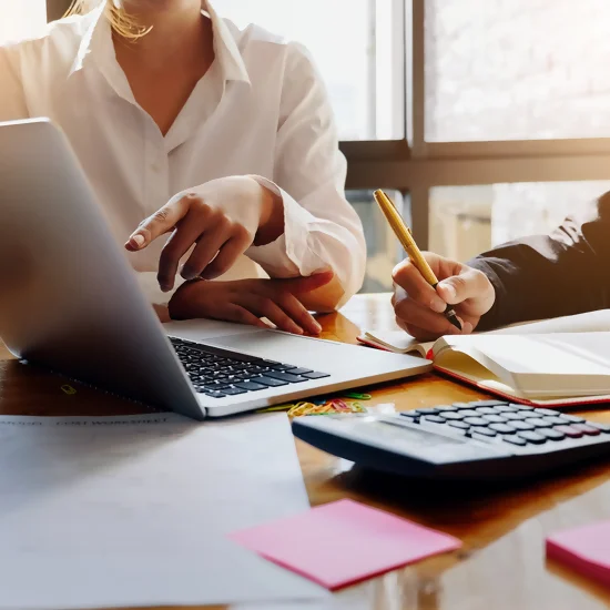 deux individus regardent un écran PC en prenant des notes